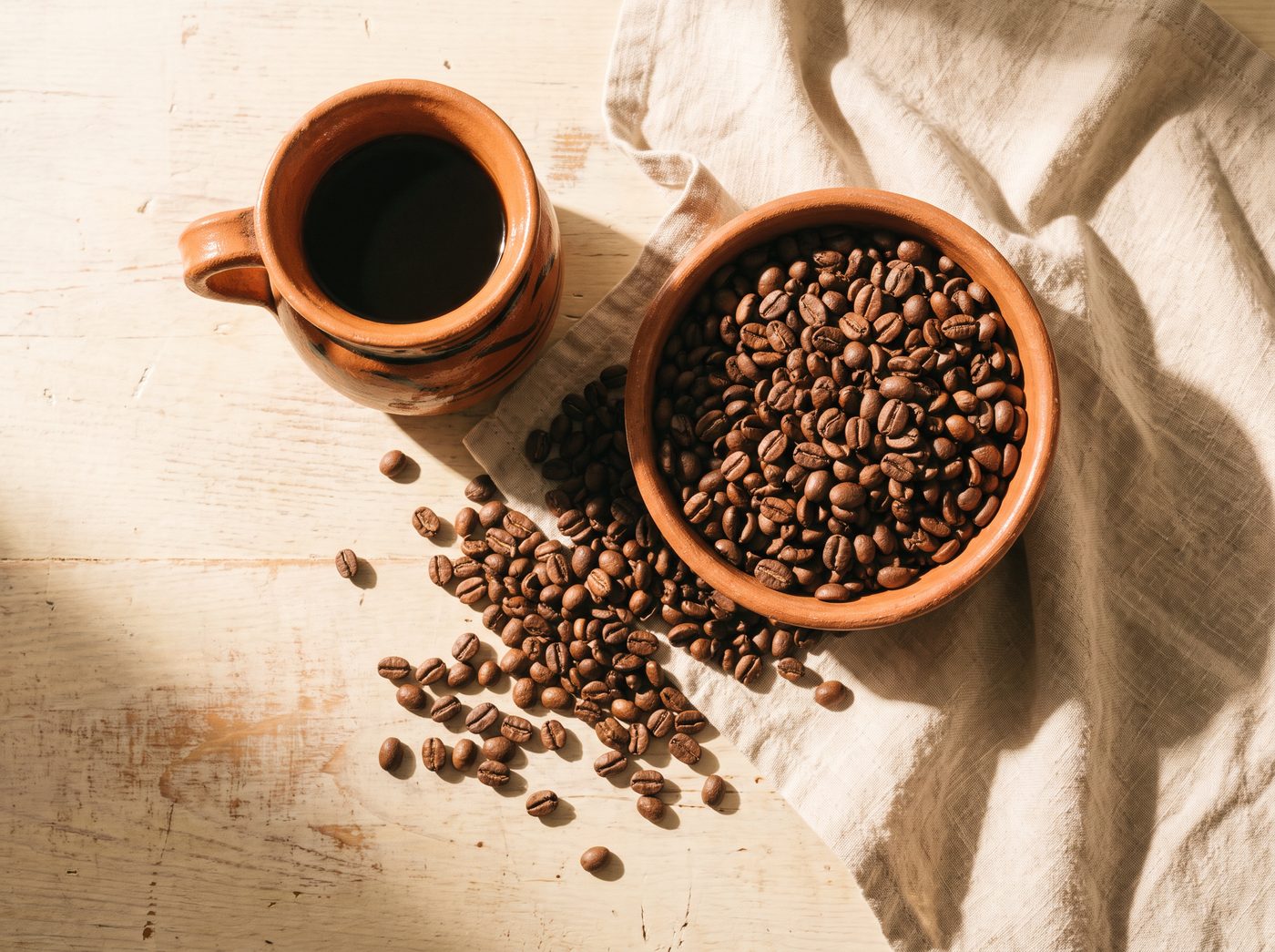 Grano de café mexicano tostado y un jarrito de barro con café